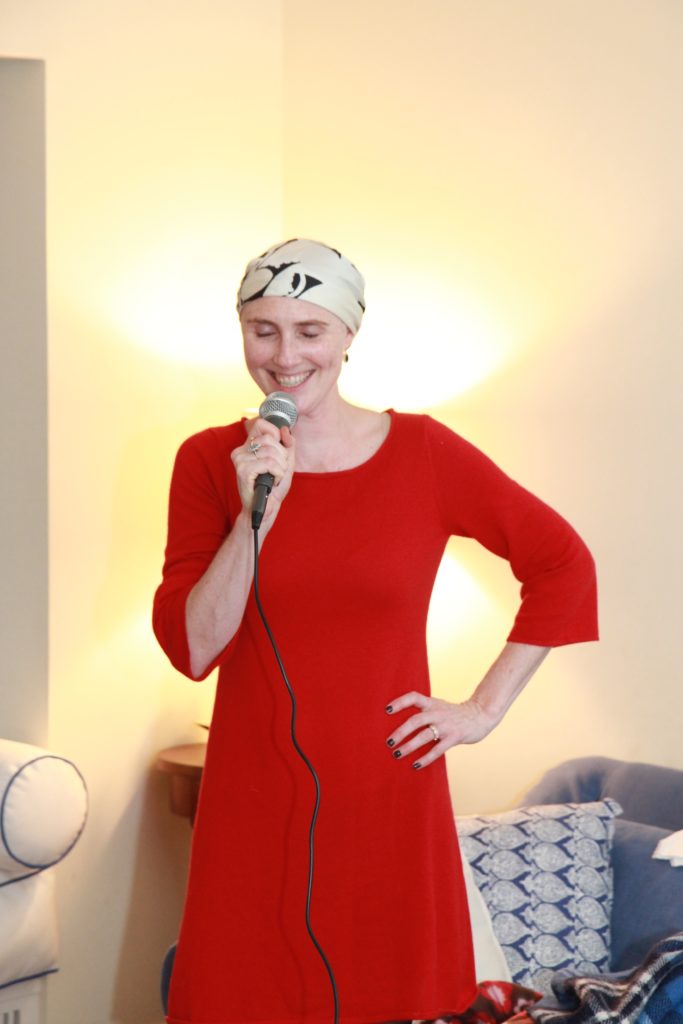 Laura standing in a red dress with a microphone, smiling and singing